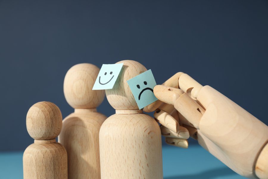 Wooden figures with contrasting happy and sad face notes, depicting the emotional ups and downs while trying to overcome dating rejection.